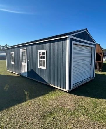 Gray shed with black doors and white-framed windows, against a gray sky.
