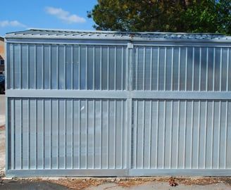 Galvanized metal fence with vertical ridges, framing a potential enclosure.