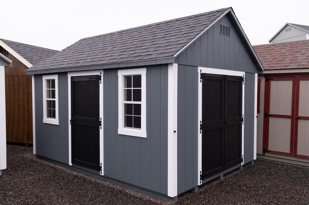 Gray shed with black doors and white-framed windows, against a gray sky.