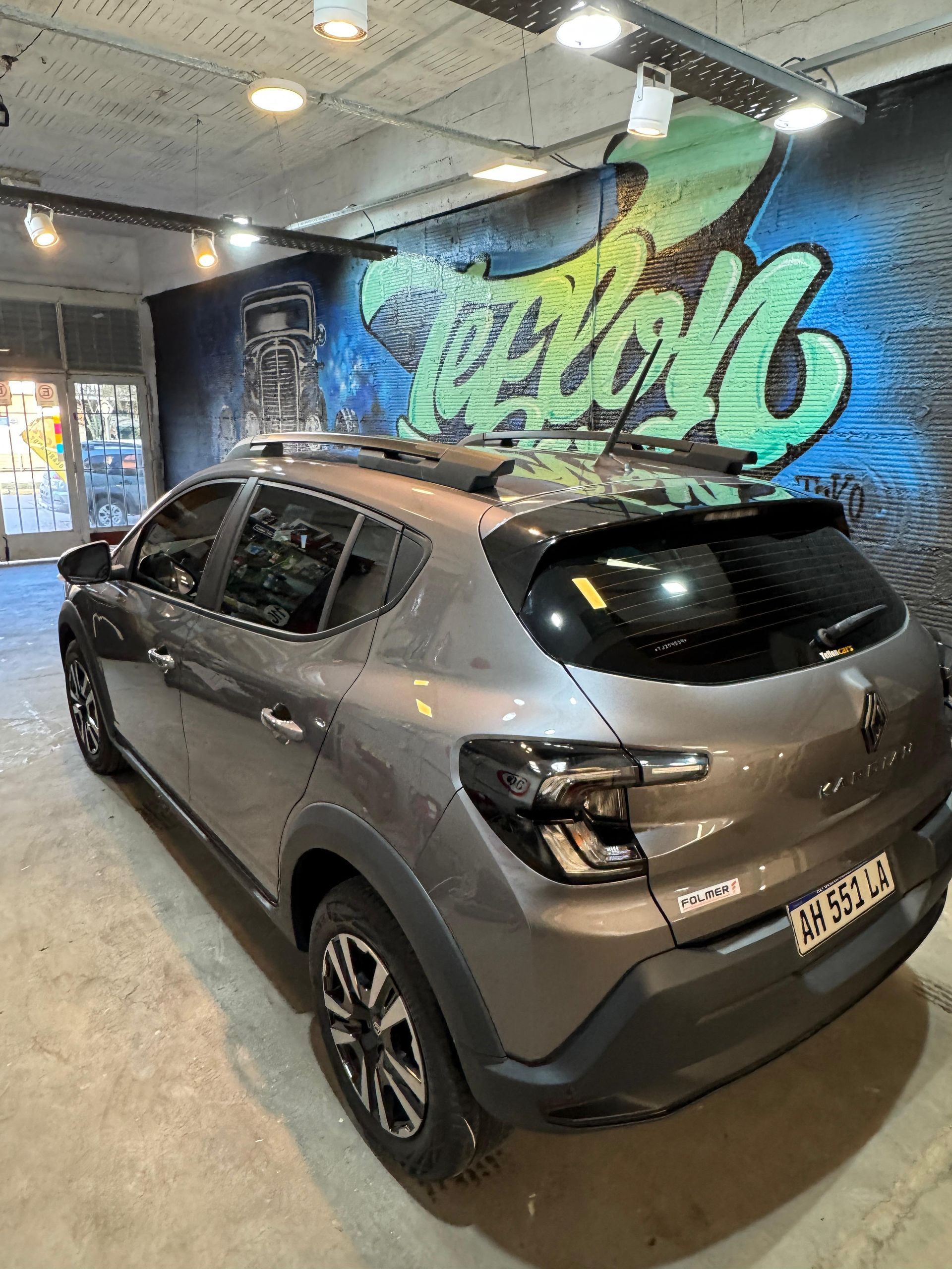 Dacia Sandero Stepway gris estacionado en el interior con grafitis en la pared.