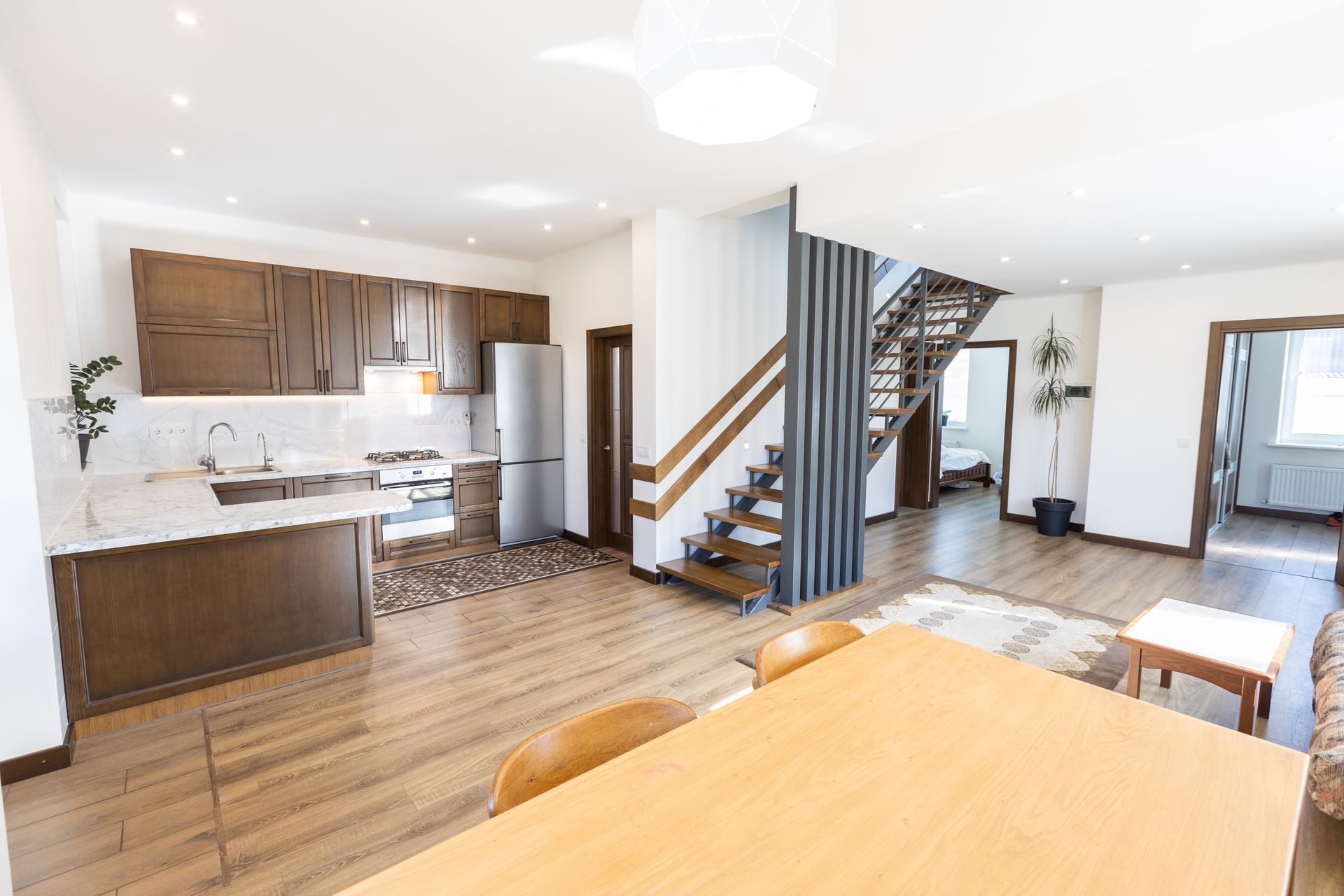 A living room with a table and chairs , a kitchen , and stairs.