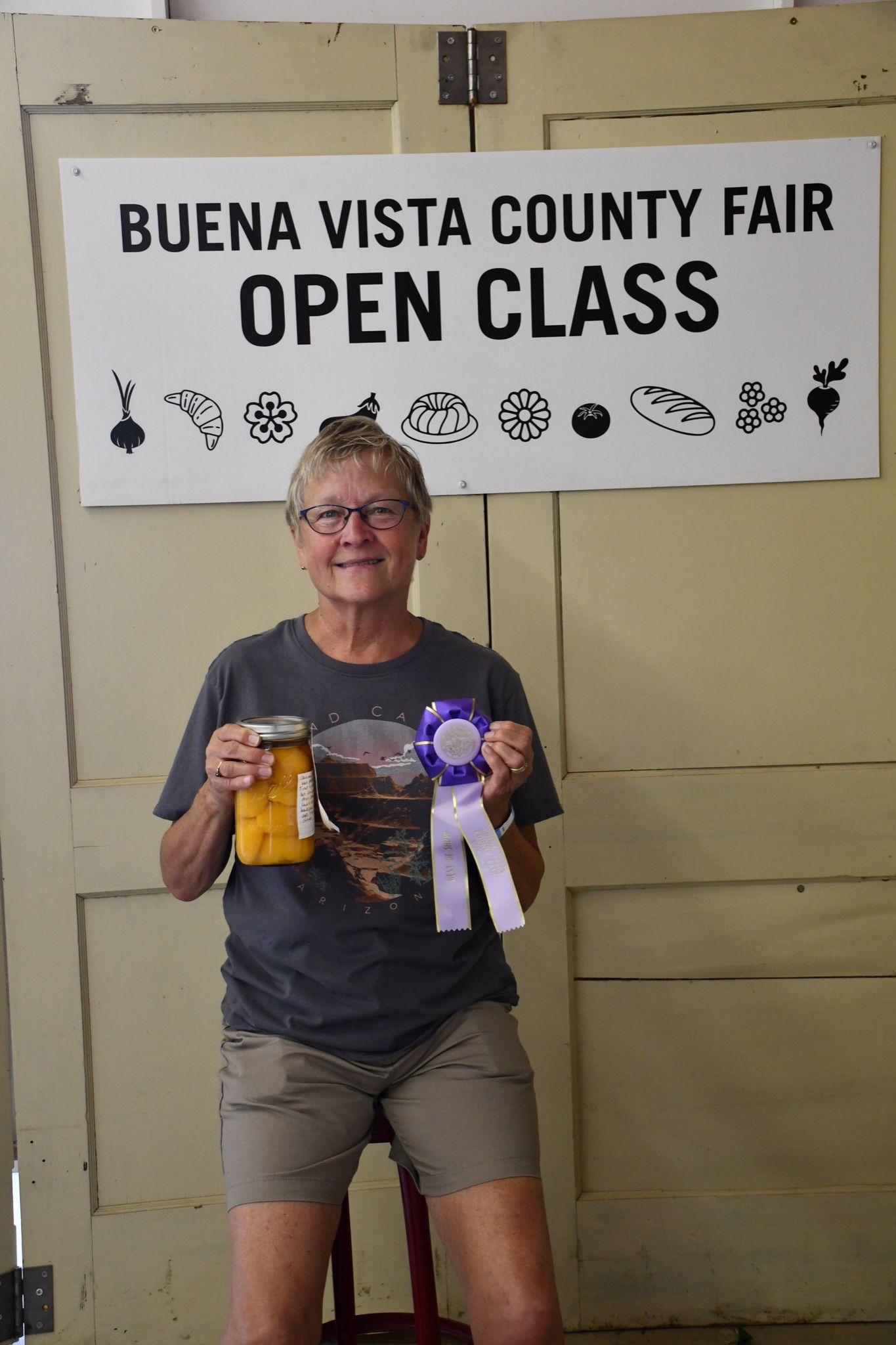 A woman is holding a ribbon in front of a sign that says buena vista county fair open class