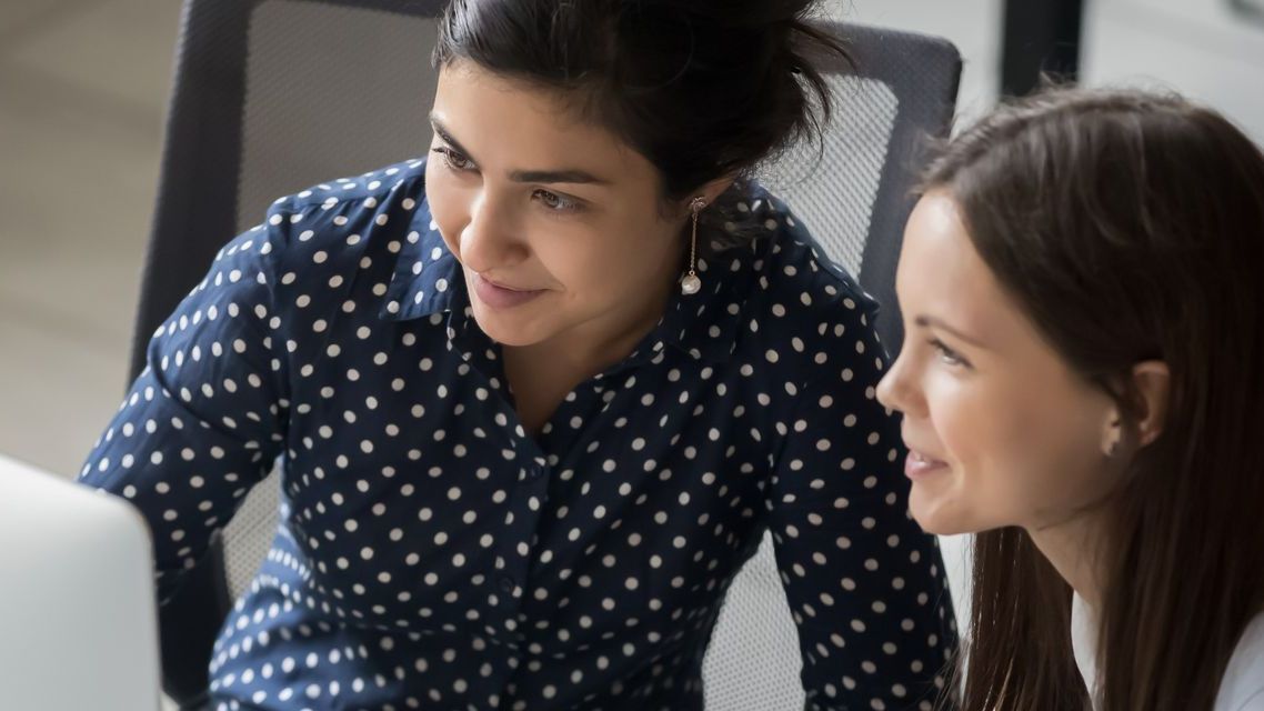 Two women are looking at a computer screen together.