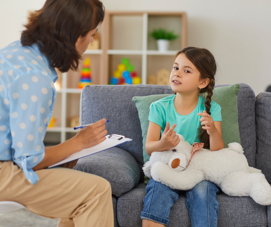 A little girl is sitting at a table talking to a woman.
