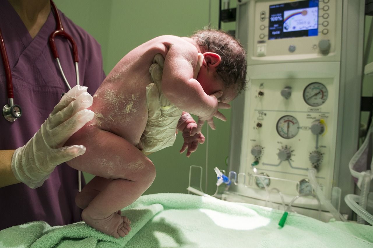 A newborn baby is being examined by a doctor in an incubator.