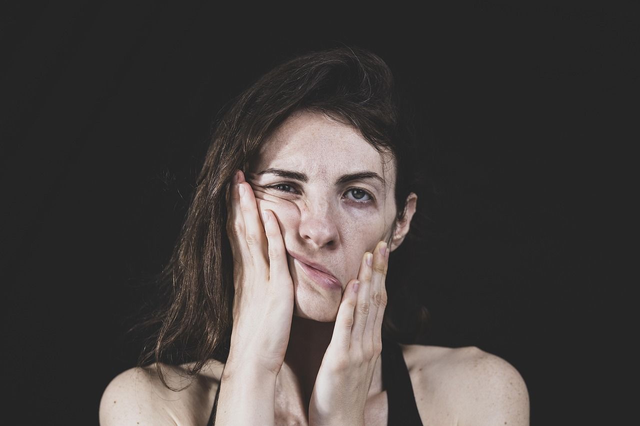 A woman is covering her face with her hands and making a funny face.