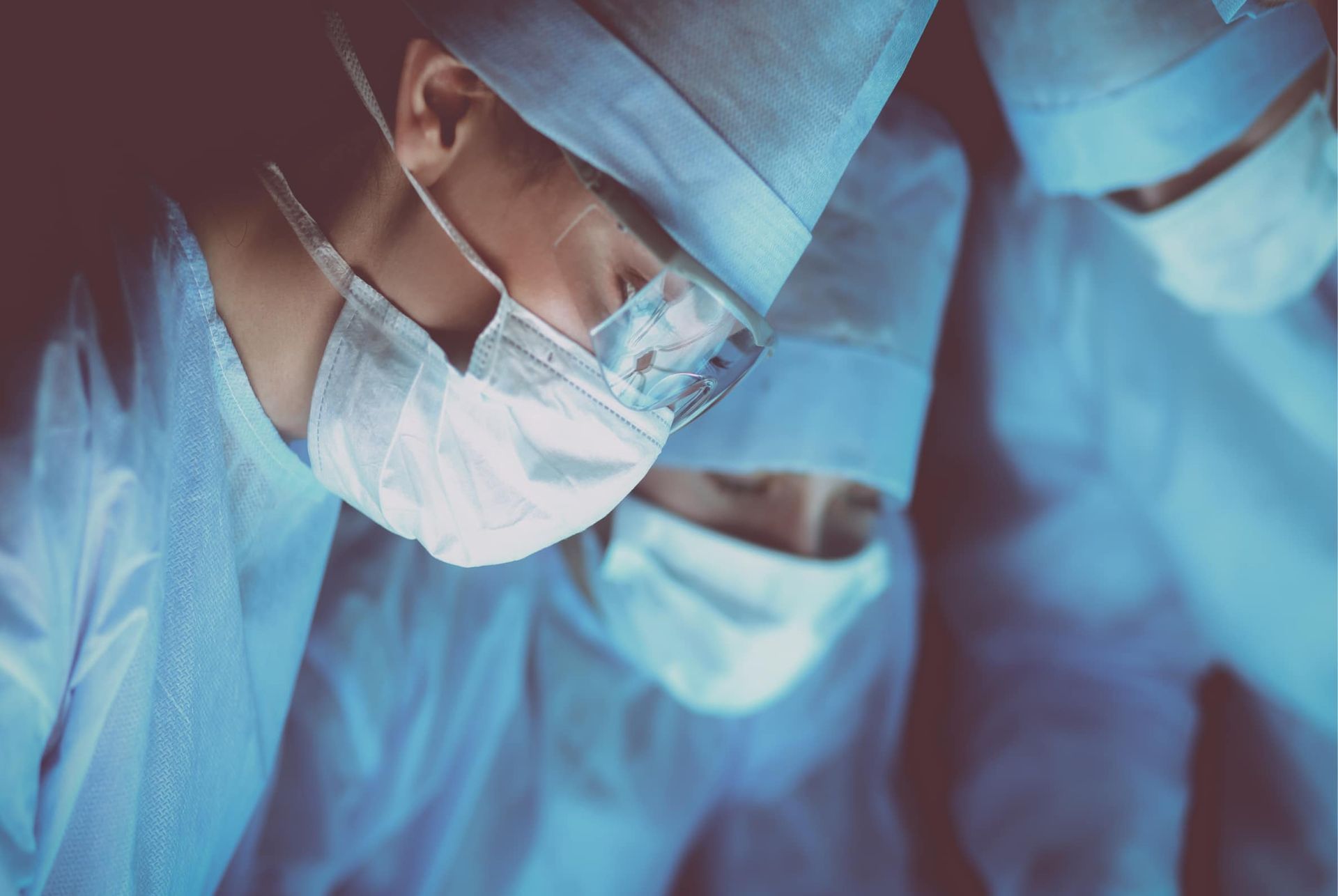 A group of surgeons wearing masks and gowns are operating on a patient.