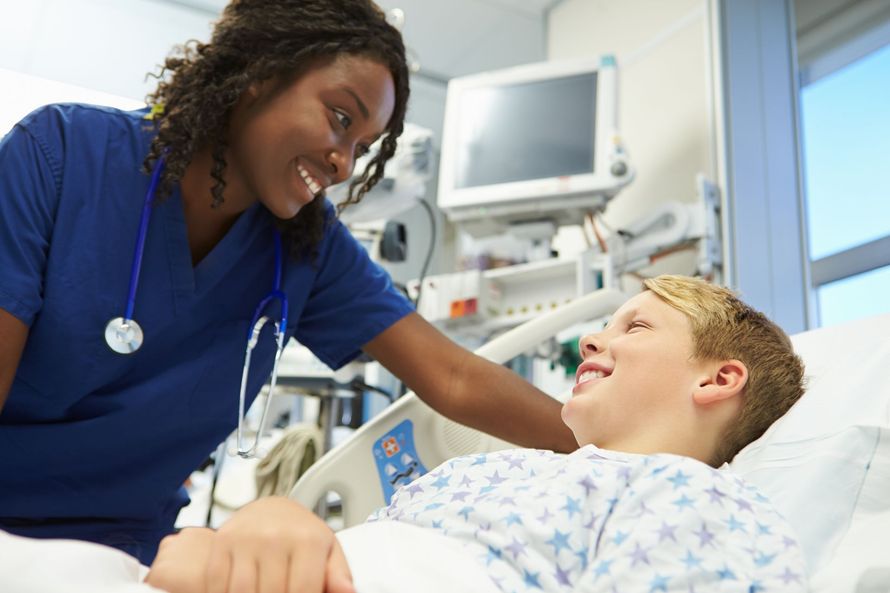A nurse is talking to a young boy in a hospital bed.
