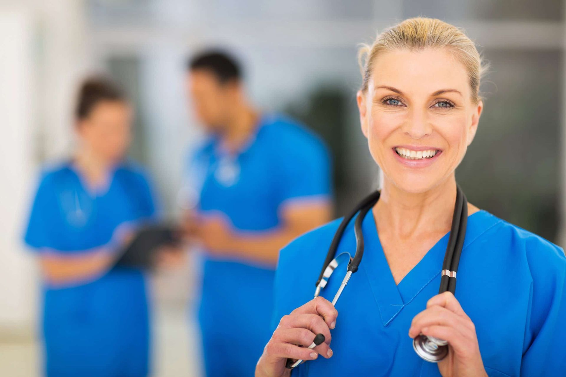 A female doctor is smiling while holding a stethoscope.