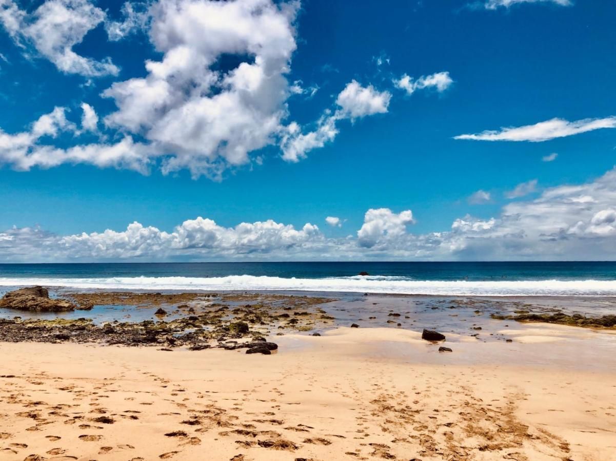 Uma praia com céu azul e nuvens ao fundo