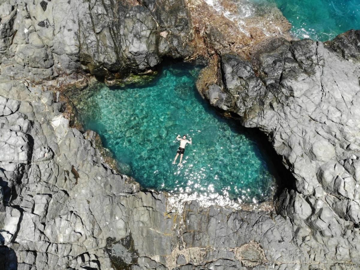 Uma vista aérea de uma pessoa nadando em uma piscina rochosa.