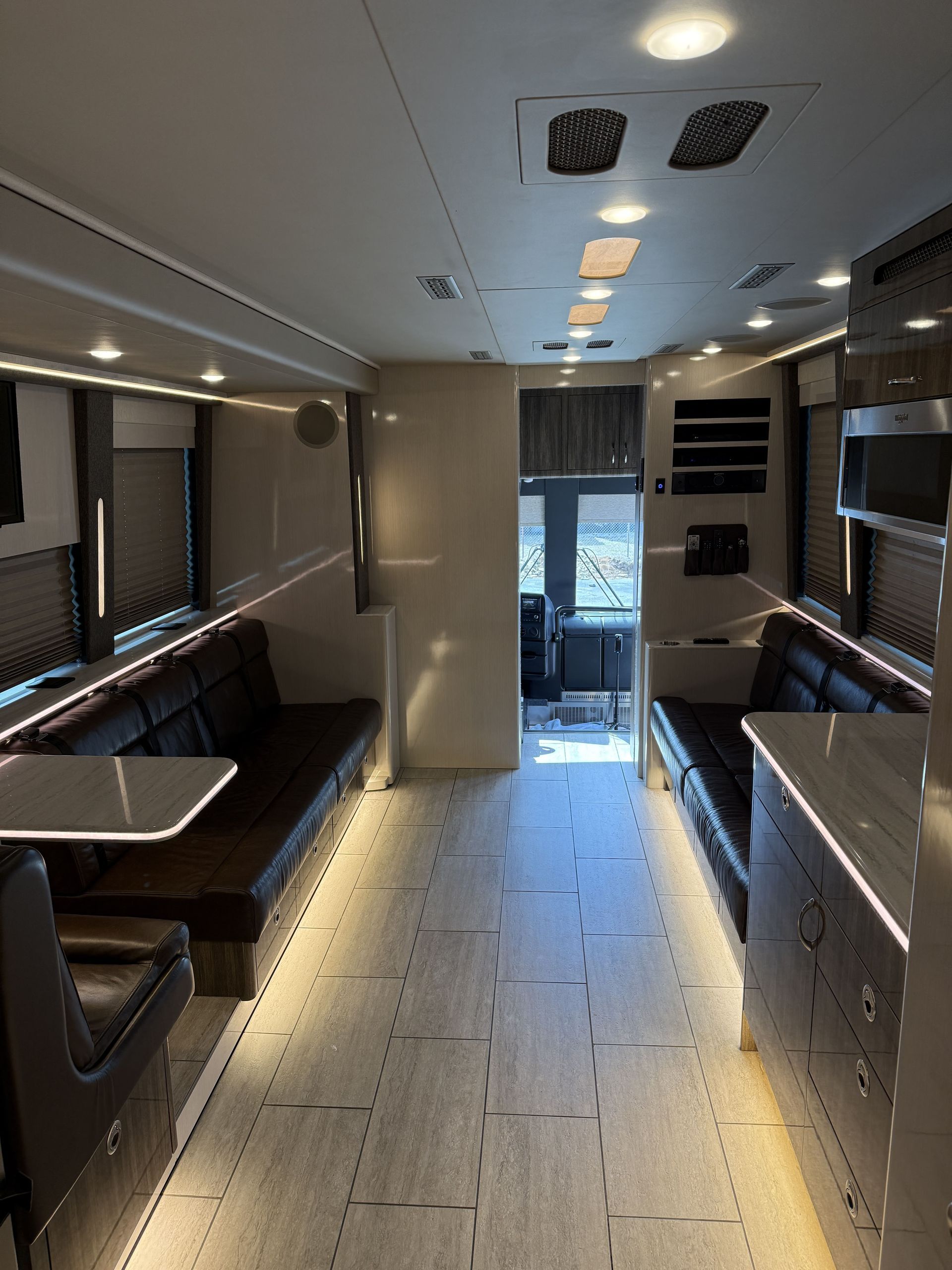 Dining area inside coach with table seating and overhead storage