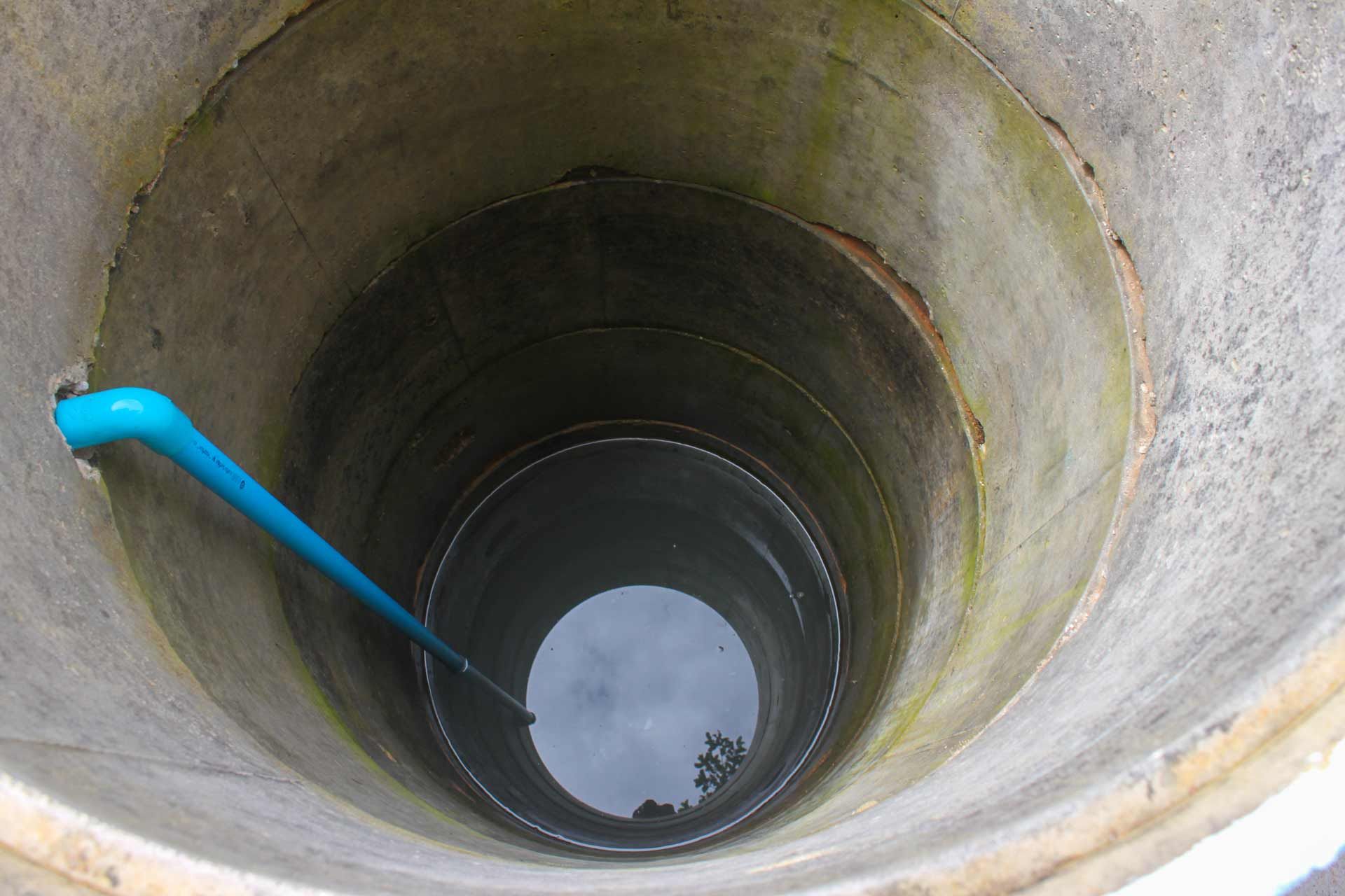A concrete well with a blue pipe