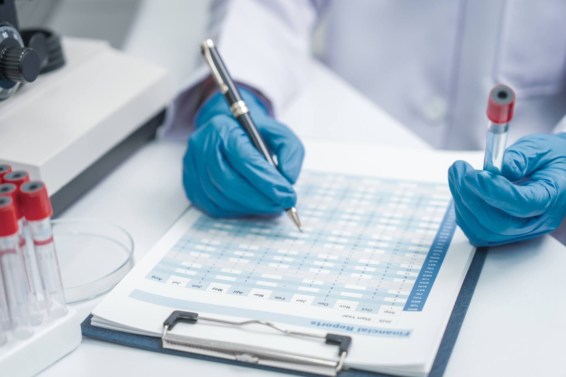 Person holding a test tube and writing on a lab form