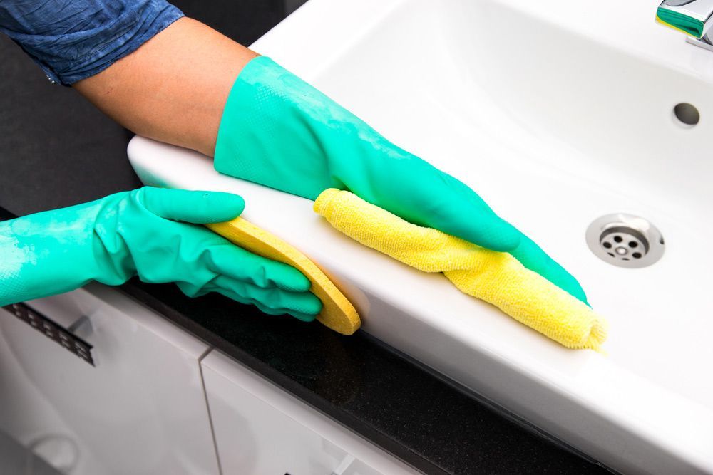 Cleaning The Bathroom Sink With A Sponge And Cloth — Jamac Cleaning Services in Cardiff, NSW
