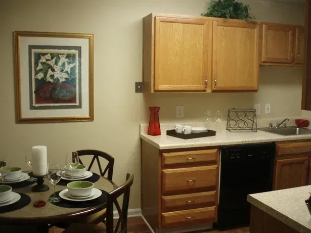 Kitchen with wooden cabinets, a dining table set, and a framed artwork on the wall.