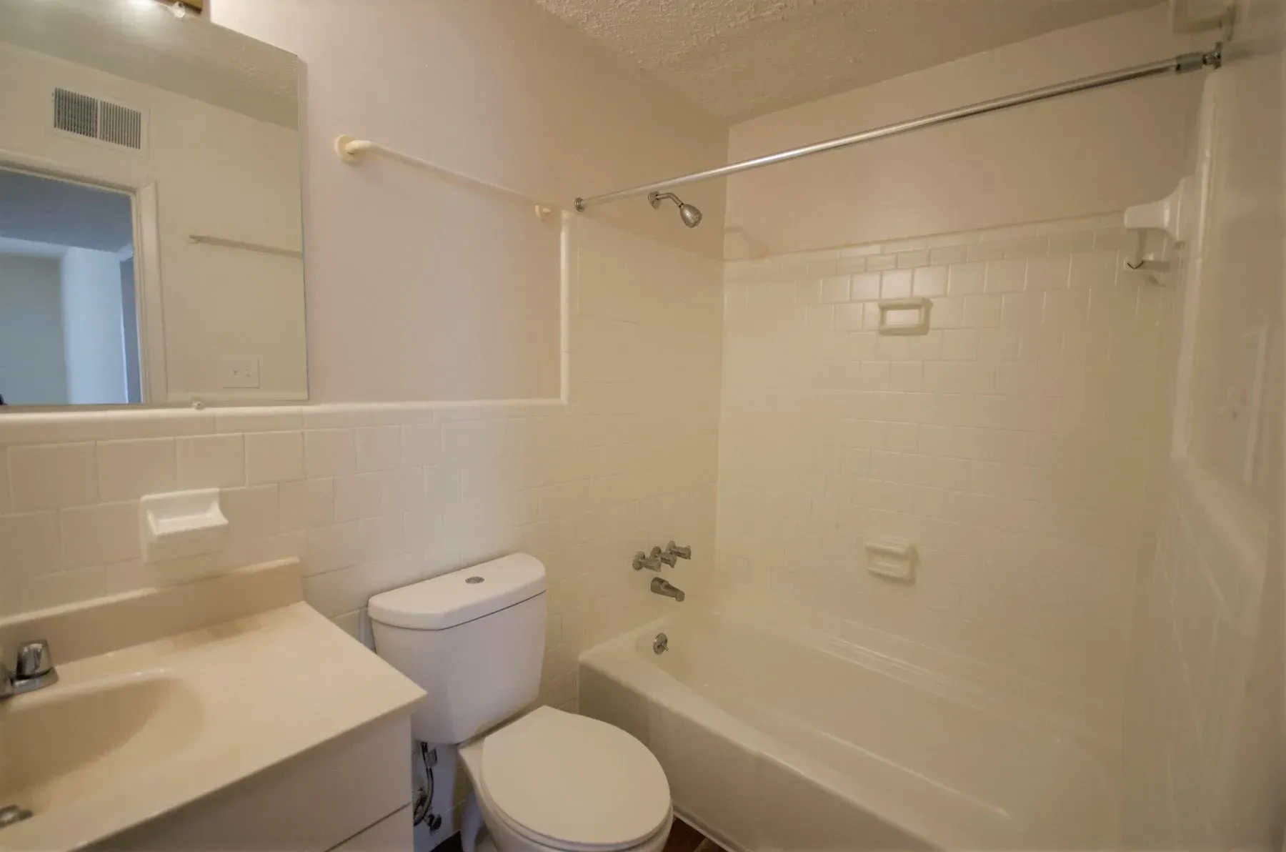 Bathroom with white fixtures: toilet, sink, and bathtub. Beige walls and tiles.