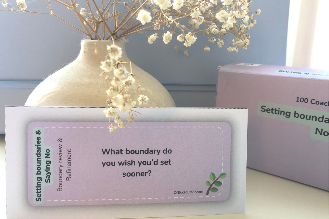 A purple bookmark is sitting on a table next to a vase of flowers.
