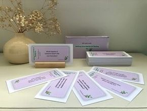 A stack of coach cards sitting on top of a table next to a vase of dried flowers.