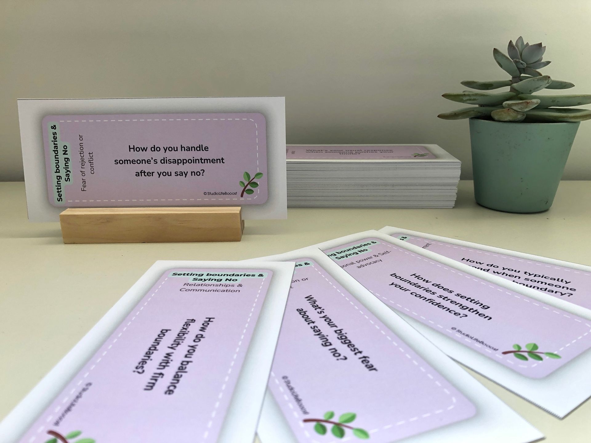 A stack of coach cards on a table next to a potted plant