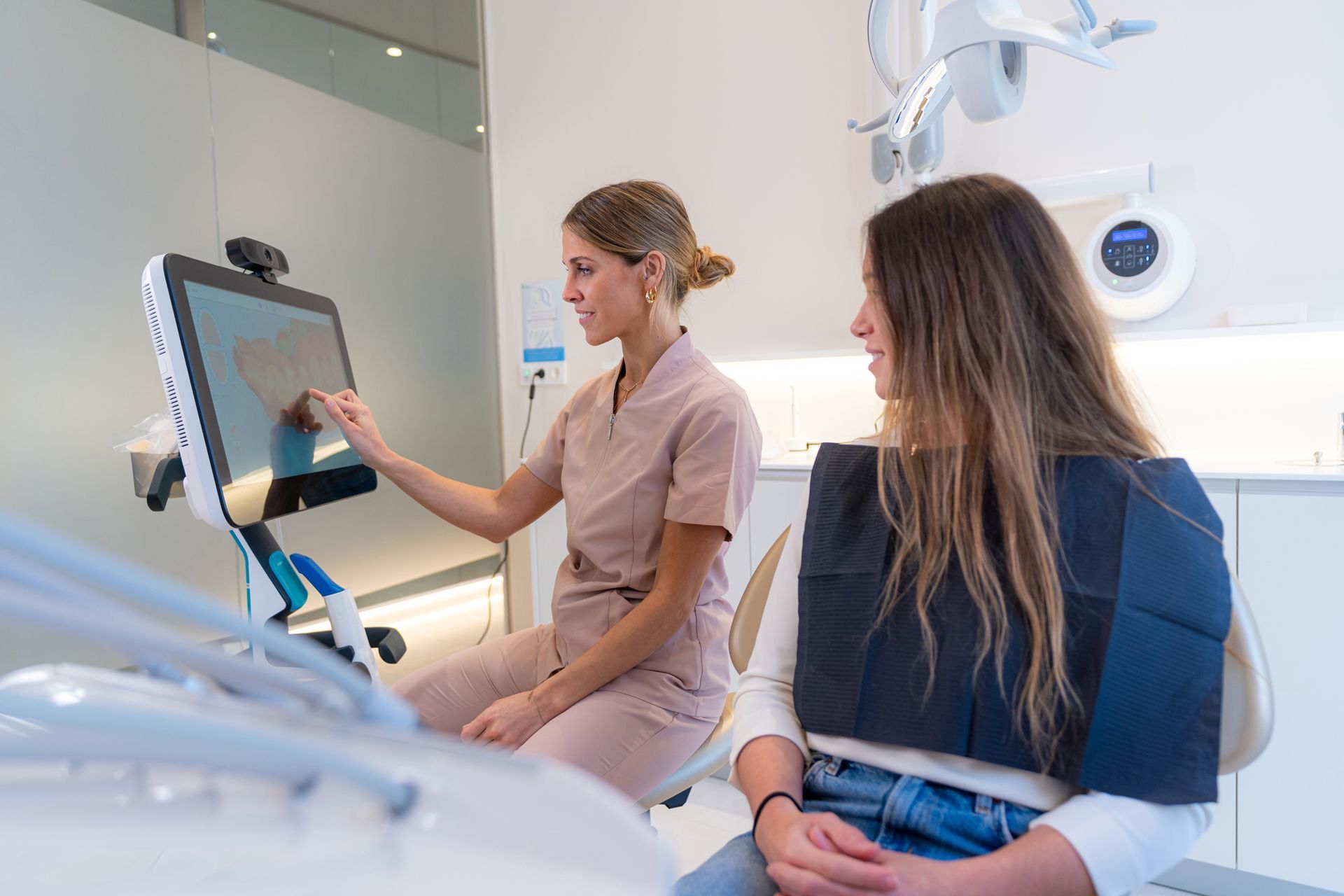 A dentist is talking to a patient in a dental chair.