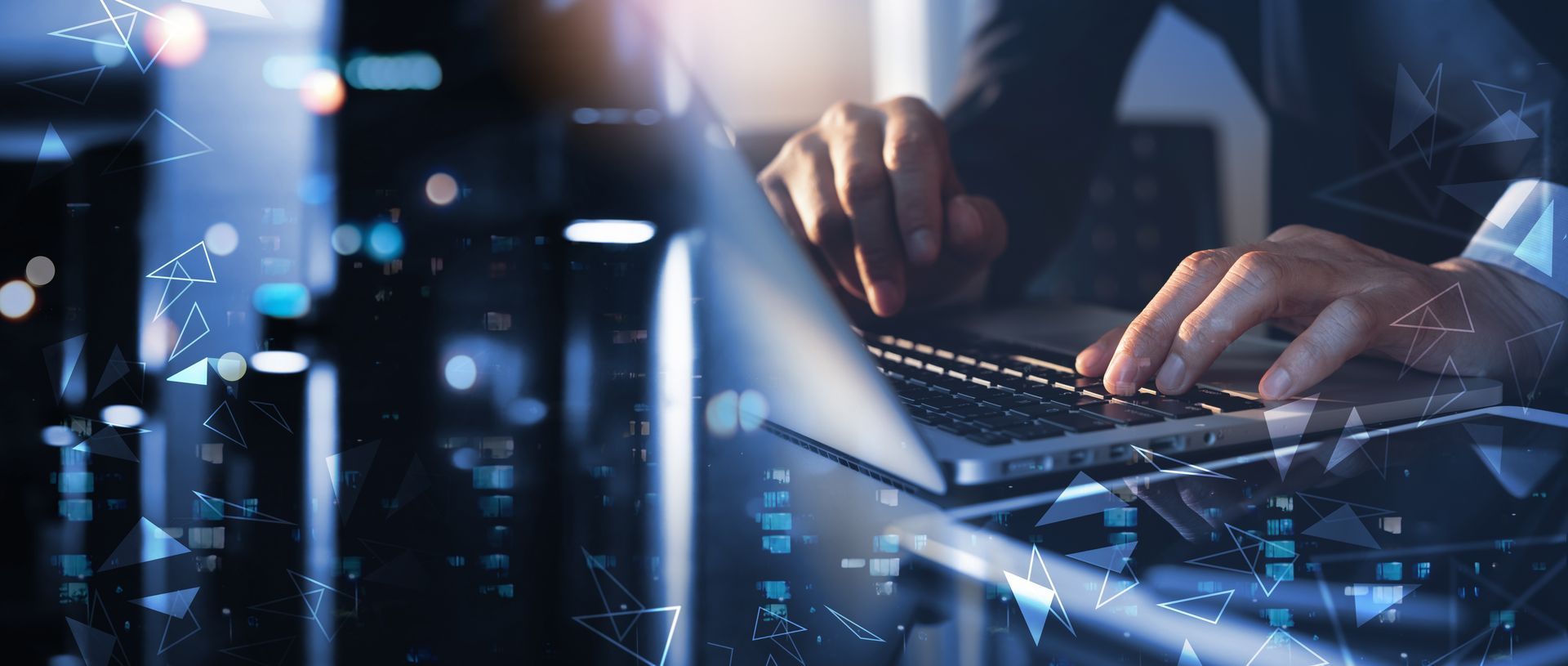 A man is typing on a laptop computer with a city in the background.