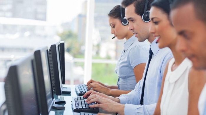 A group of people are working on computers in a call center.