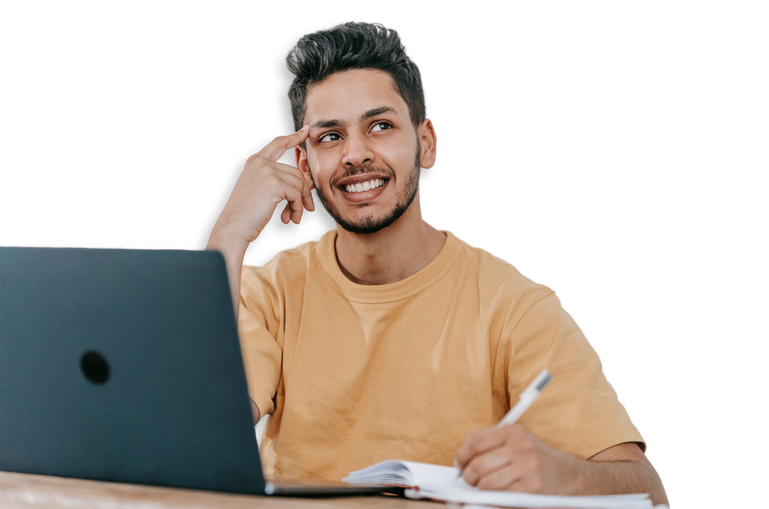 A man is sitting at a desk with a laptop and a notebook.