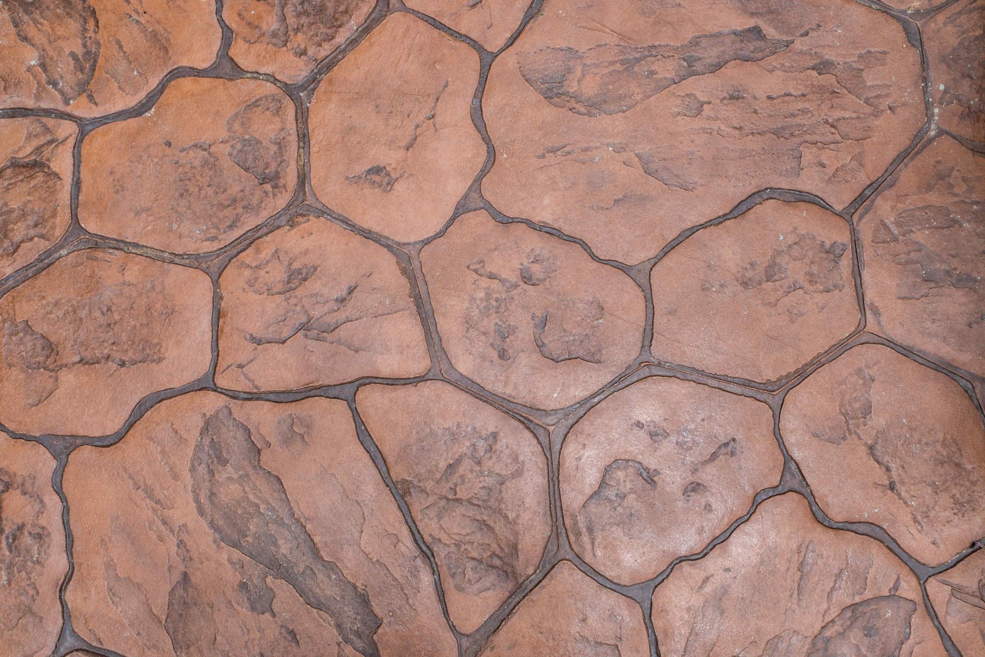 Stamped concrete surface with an irregular, rustic stone pattern in shades of reddish-brown and gray.
