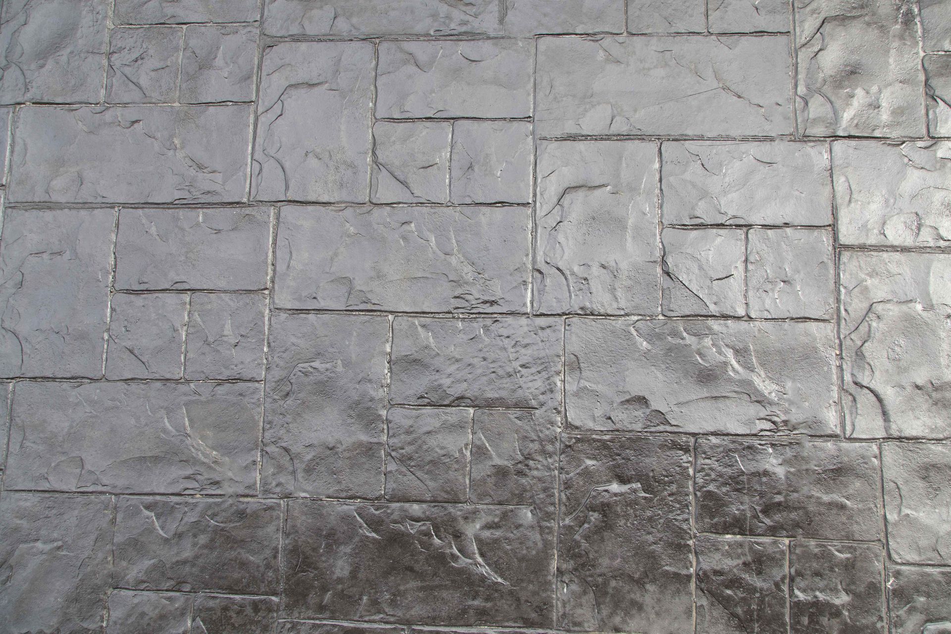 Gray concrete surface with an embossed pattern of rectangular stones of various sizes.