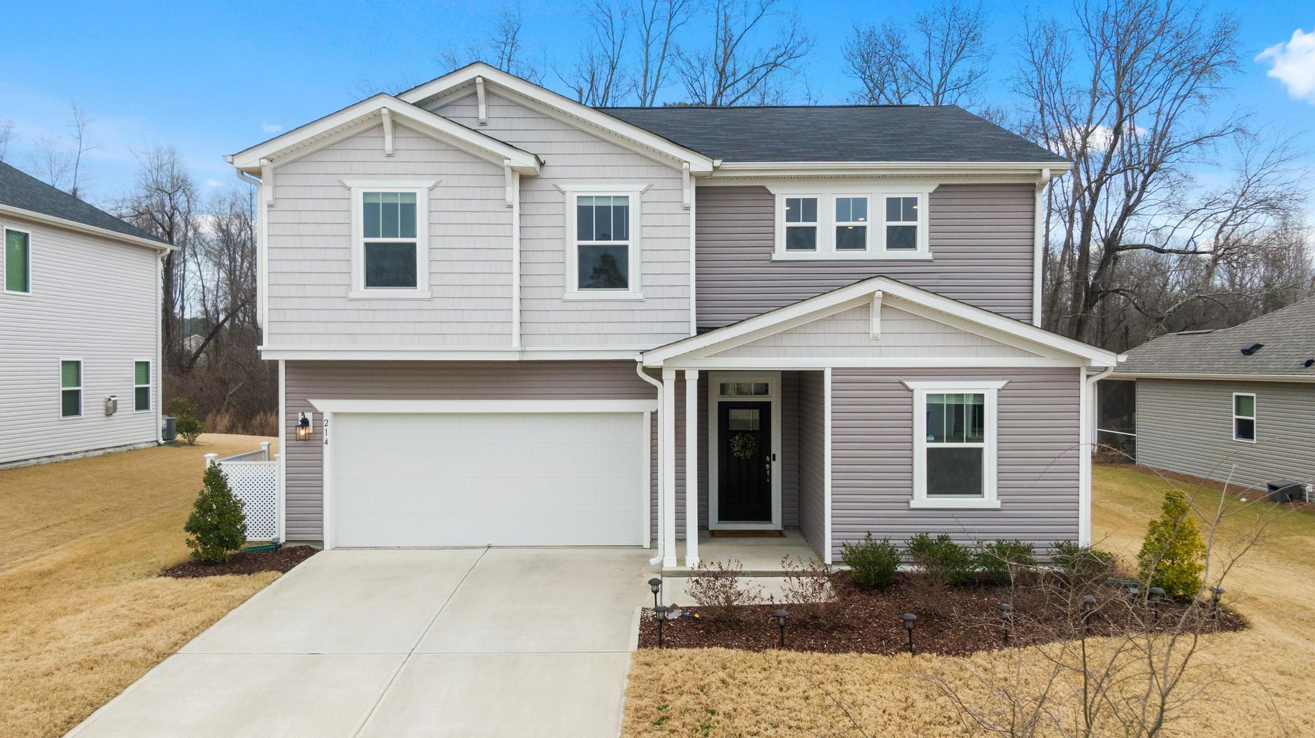 Two-story suburban house with light gray horizontal siding, white trim, a two-car garage, and a small front yard.