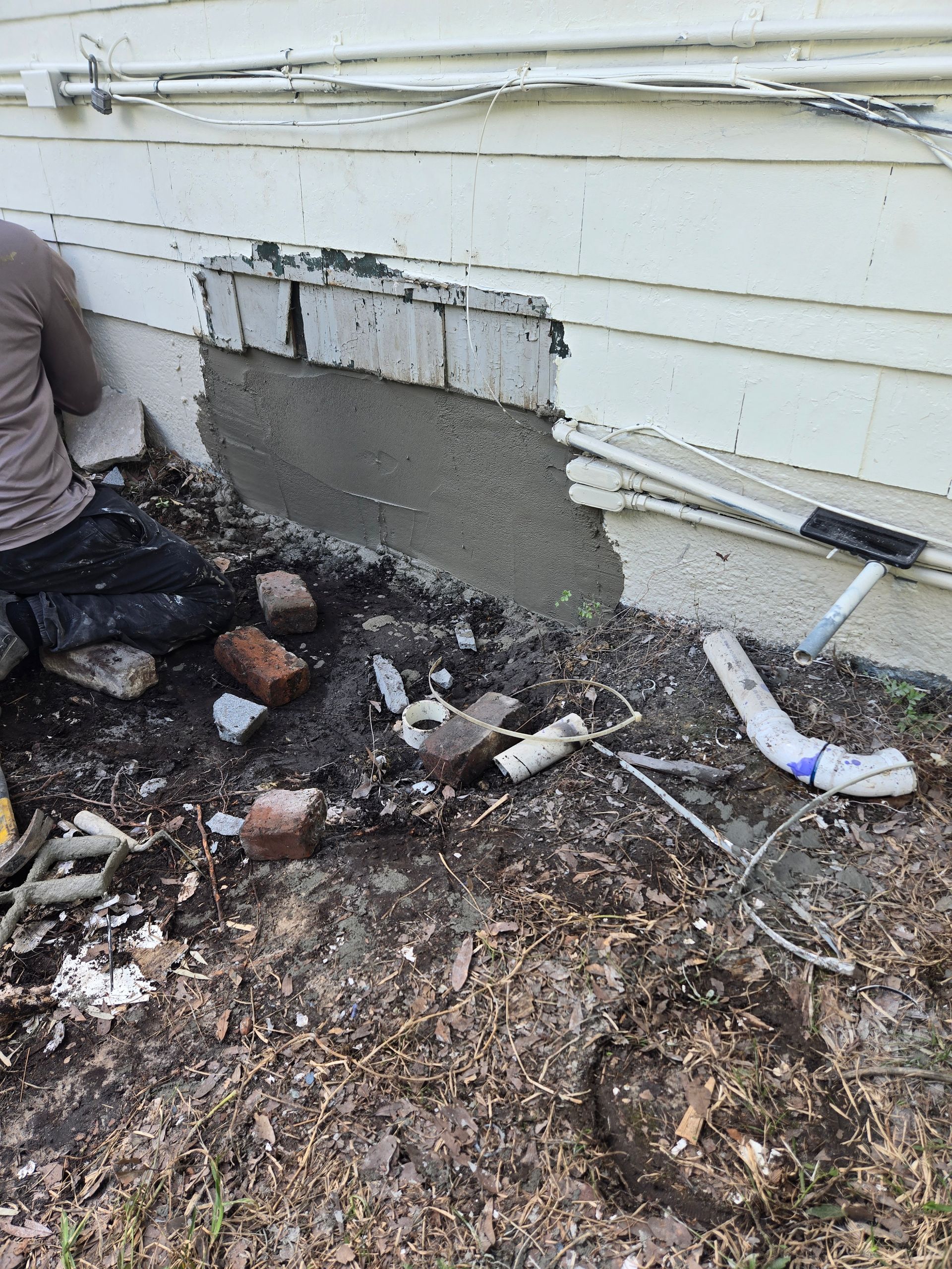A man is kneeling down and painting a wall with a roller.