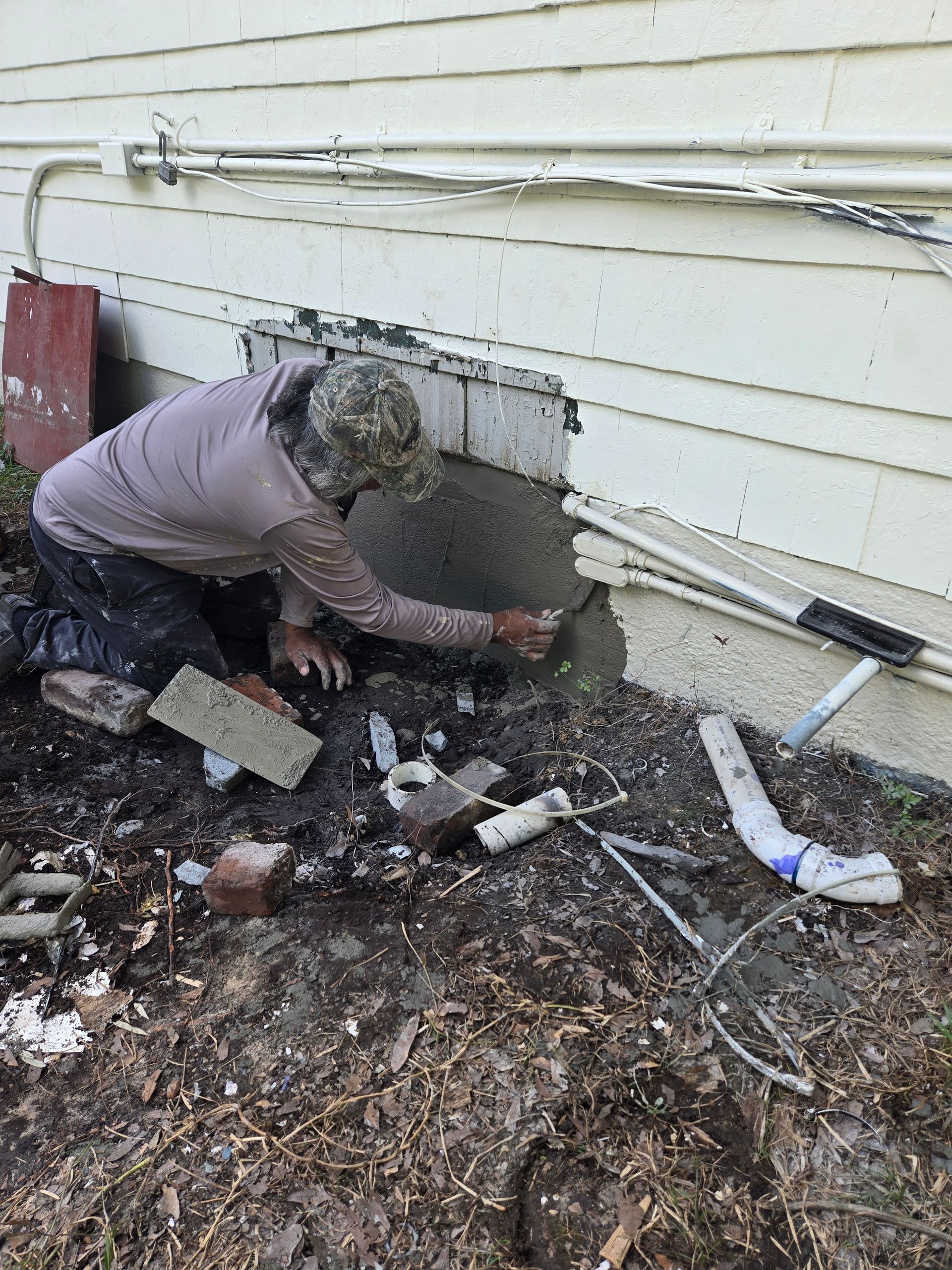 A man is kneeling down and painting a wall with a roller.