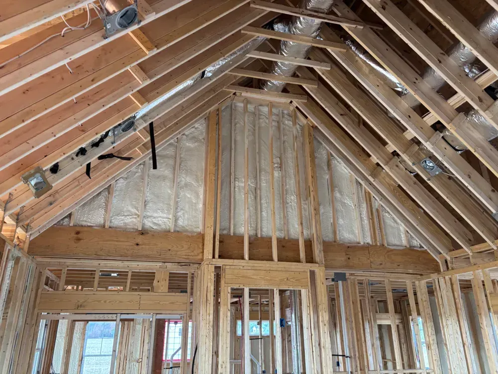 Unfinished attic with exposed wooden roof trusses and wall framing under construction