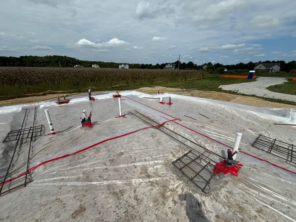 Construction site with concrete slab, rebar grids, red safety straps, and cloudy sky overhead