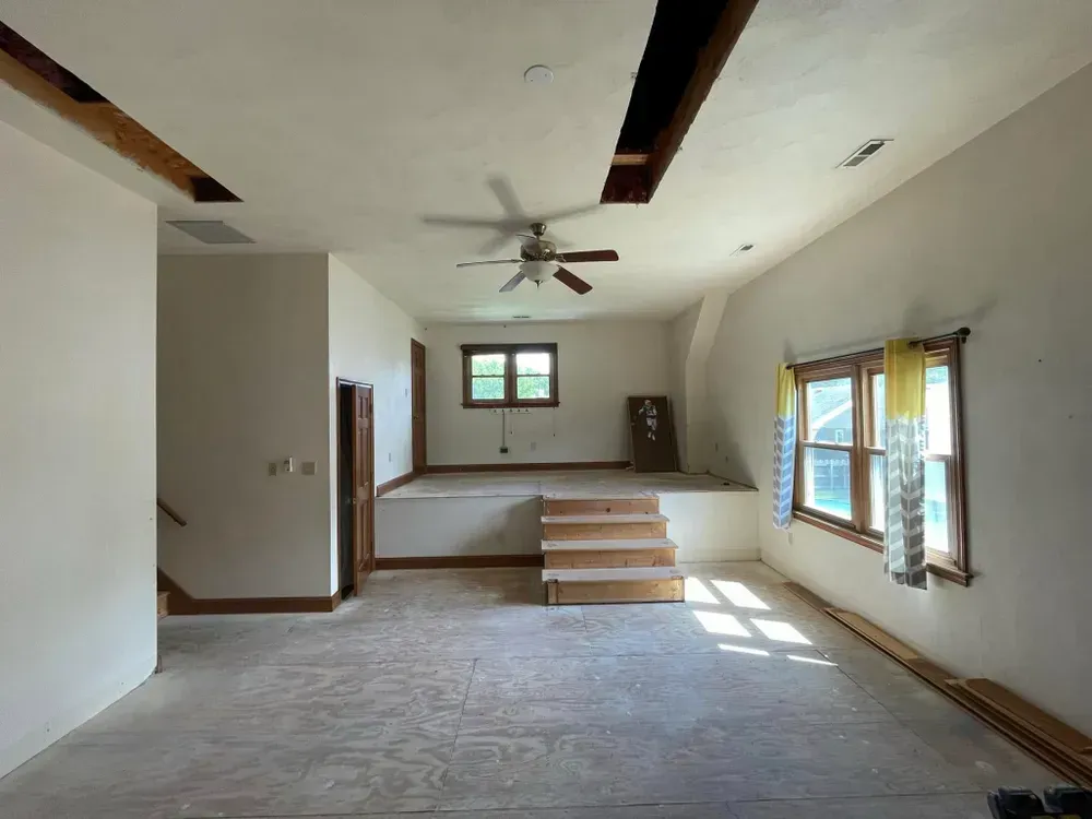 Empty living room with carpet, ceiling fan, fireplace, and sunlight through windows