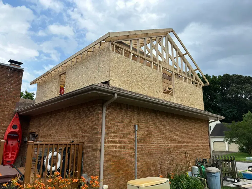 Brick house with new second-story framing and roof trusses under construction