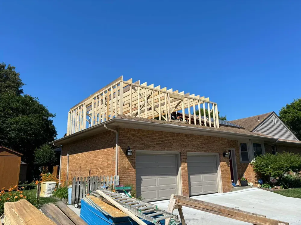 Brick house with a new wooden roof frame under construction on a sunny day