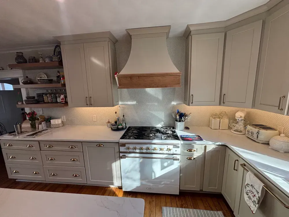 Bright white kitchen with cream cabinets, gas stove, island, and wooden countertops in daylight