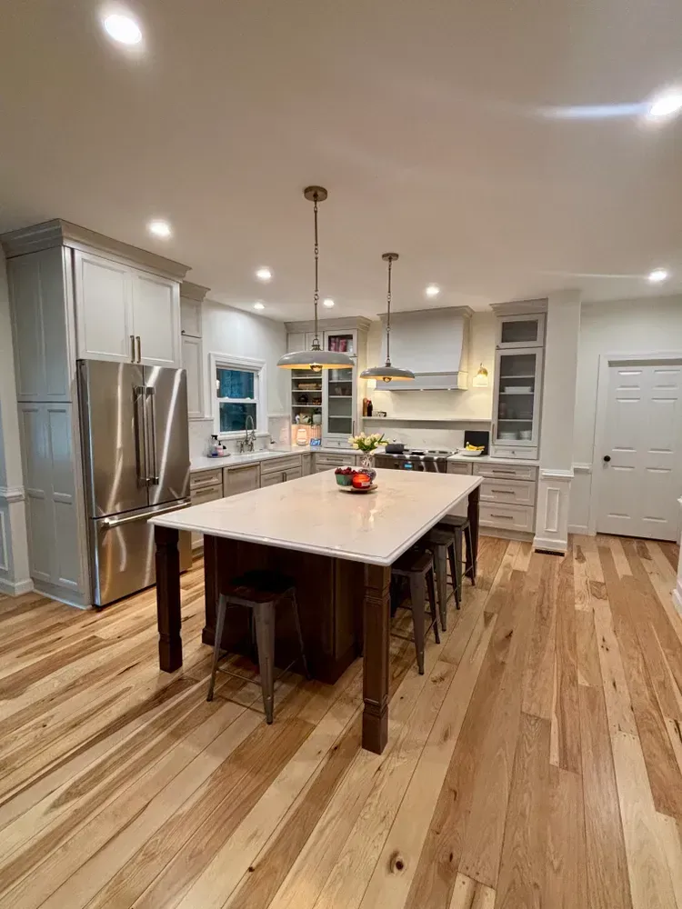 Bright modern kitchen with stainless steel appliances, large island, white cabinets, and hardwood floors