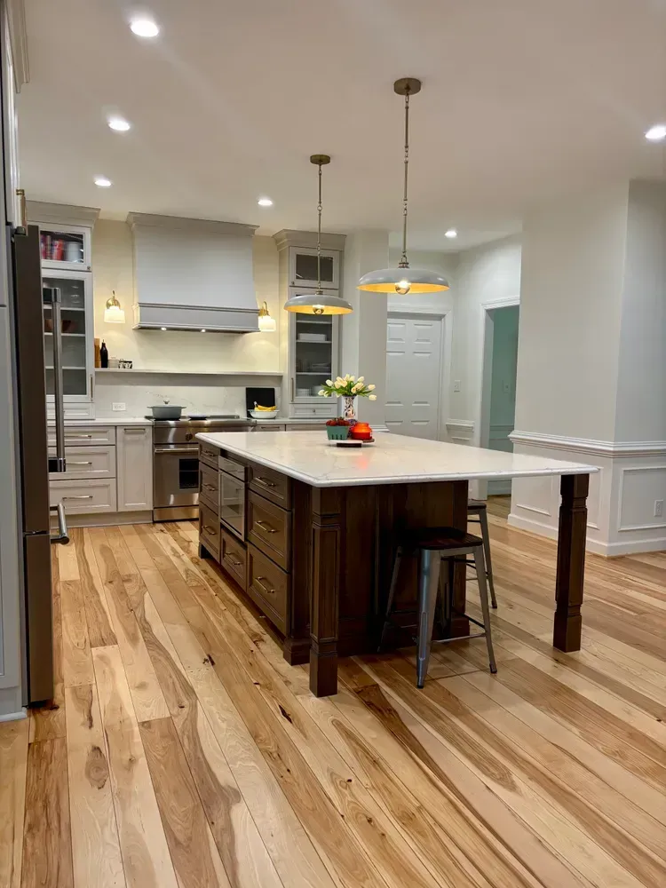 Modern kitchen with a large island, pendant lights, stainless appliances, and hardwood floors