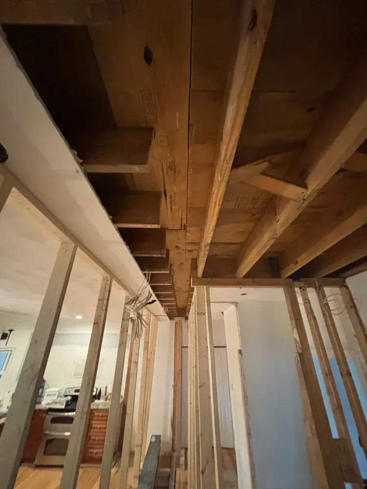 Unfinished room with exposed wooden ceiling joists and wall studs during construction.
