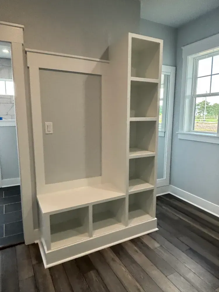 White built-in desk and shelving unit in a bright room with gray walls and wood flooring