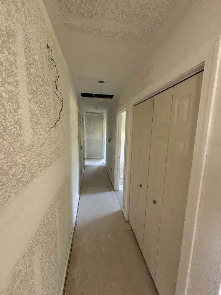 Narrow beige hallway with closed closet doors and a bright doorway at the end