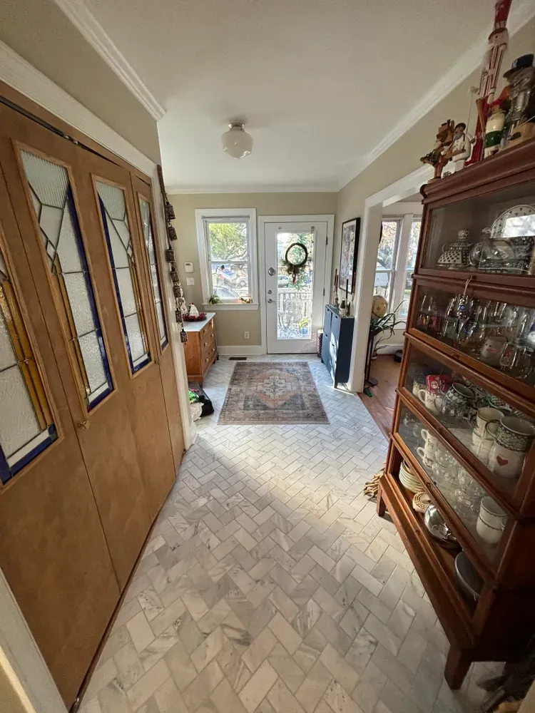 Narrow hallway with wooden cabinets, patterned rug, and a glass door at the far end