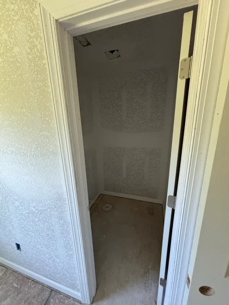 Open doorway to a small unfinished closet with bare walls and carpeted floor