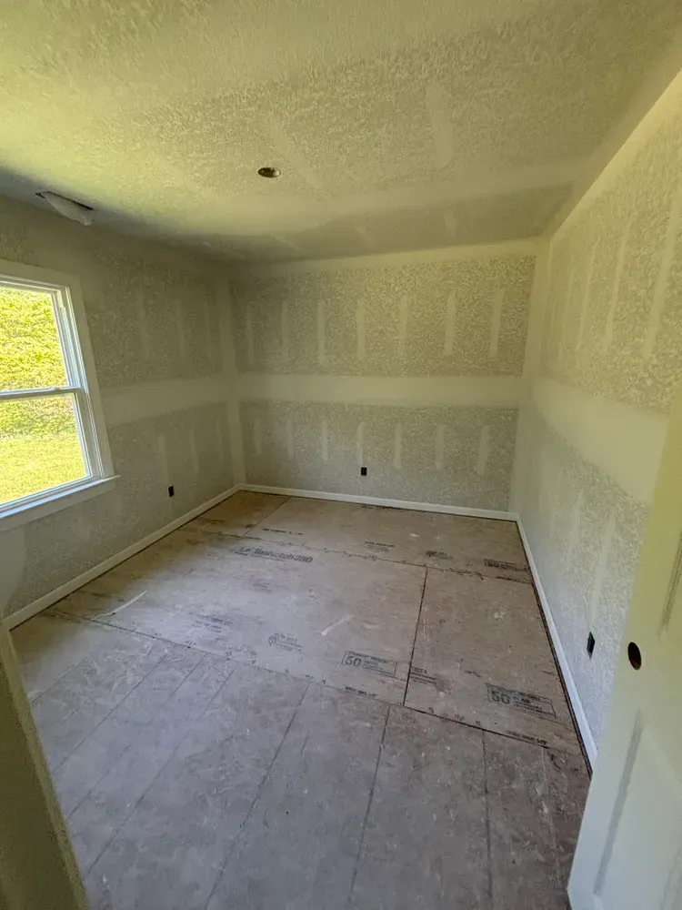 Empty white room with unfinished floor and yellow-tinted window light