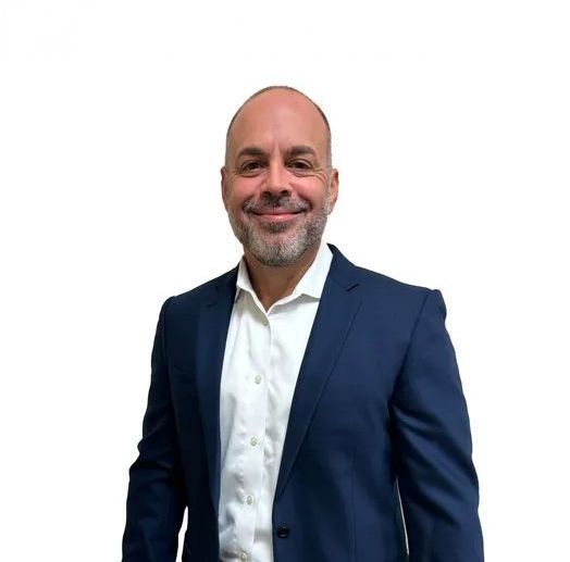 A man in a suit and white shirt is smiling for the camera.