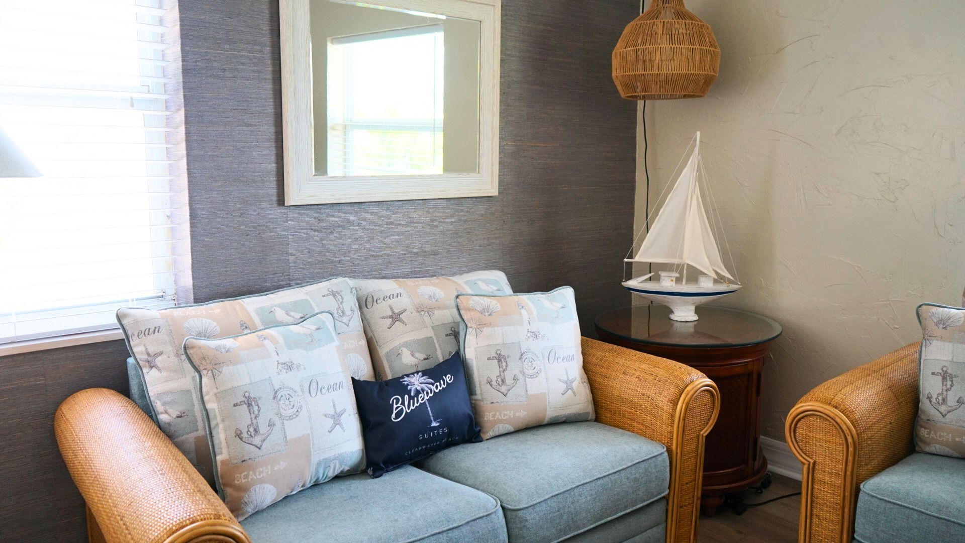 A living room with a couch , chairs , and a sailboat on a table.