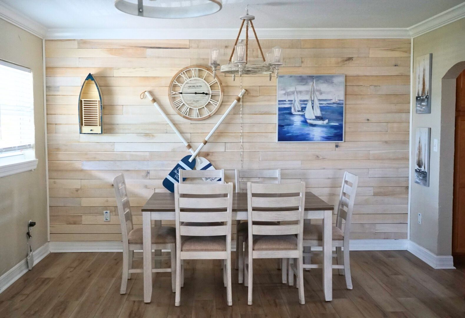 A dining room with a table and chairs and a clock on the wall.